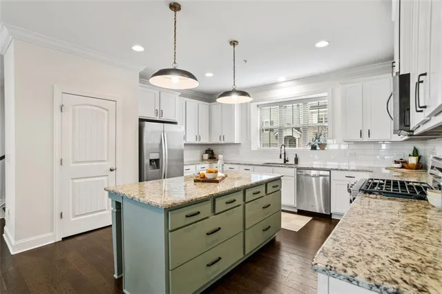 a kitchen with kitchen island granite countertop a sink a counter space appliances and cabinets