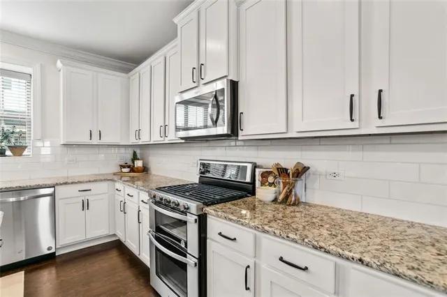 a kitchen with stainless steel appliances granite countertop white cabinets sink and dishwasher