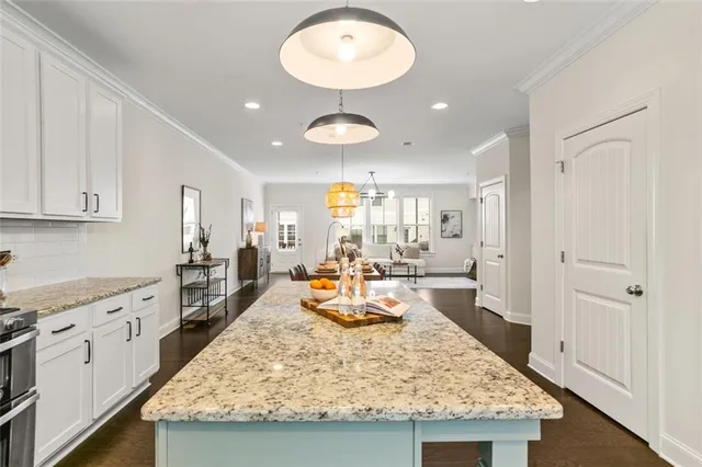 a large kitchen with kitchen island a stove a sink dishwasher and white cabinets with wooden floor