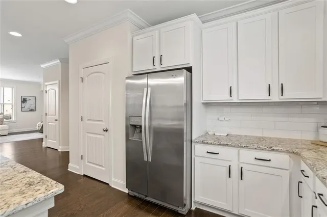 a kitchen with stainless steel appliances granite countertop a refrigerator a stove and white cabinets