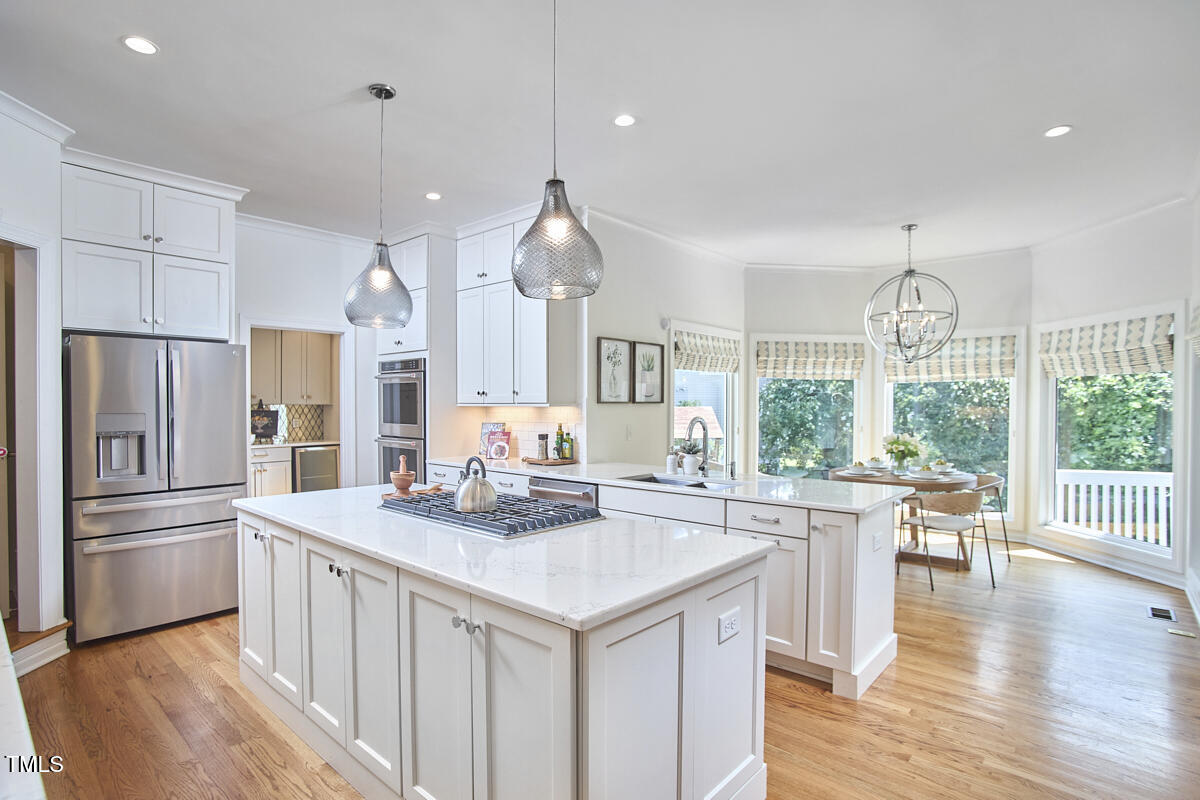 4303 Thetford Road Durham, NC 27707 - Photo 27 of 88 a kitchen with stainless steel appliances granite countertop a stove a refrigerator a sink dishwasher and a dining table with wooden floor