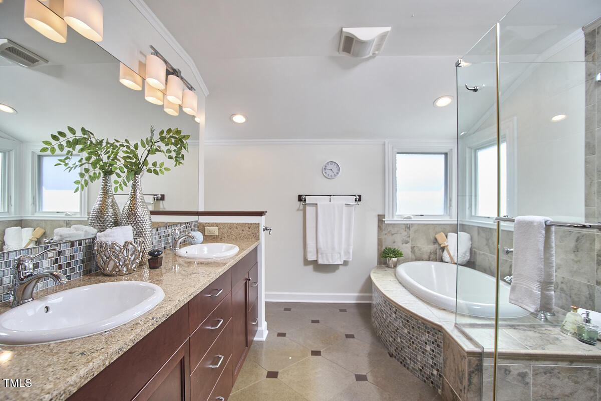 4303 Thetford Road Durham, NC 27707 - Photo 44 of 88 a bathroom with a granite countertop tub a double vanity sink a window and a mirror