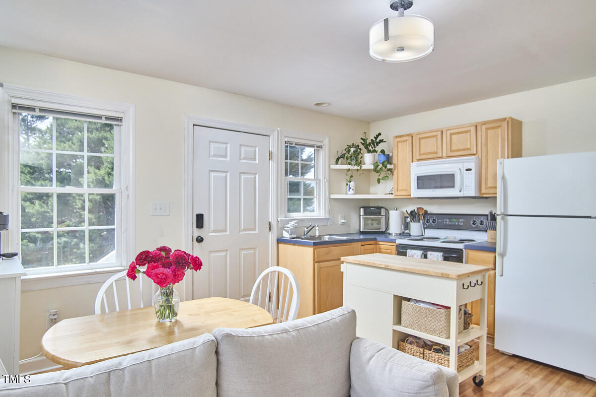 4303 Thetford Road Durham, NC 27707 - Photo 81 of 88 a kitchen with a stove a refrigerator and a dining table with wooden floor