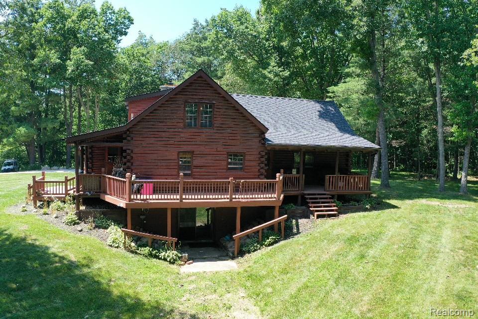 3656 Stanley Road Columbiaville, MI 48421 - Photo 56 of 65 Log-style exterior featuring a covered front porch, a multi-level wooden deck, and an asphalt shingle roof