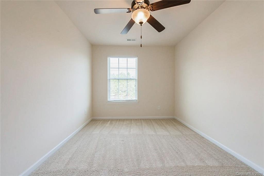 130 Inlet Point Drive Tega Cay, SC 29708 - Photo 10 of 13 an empty room with chandelier fan and windows