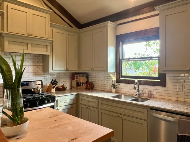 a kitchen with stainless steel appliances granite countertop white cabinets and a stove top oven