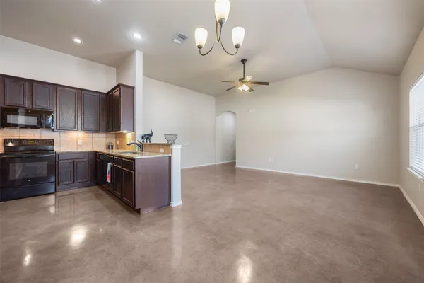 a view of a livingroom with a ceiling fan a kitchen space and a ceiling fan