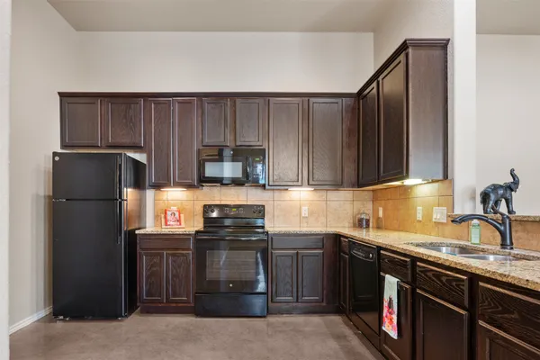 a kitchen with stainless steel appliances granite countertop a refrigerator a sink dishwasher a stove top oven a sink and dishwasher