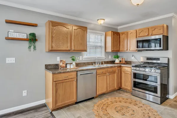 a kitchen with stainless steel appliances granite countertop a stove a sink and a microwave