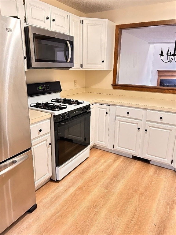 15 A Hawthorne Village, Unit D Franklin, MA 02038 - Photo 7 of 18 a kitchen with granite countertop white cabinets stainless steel appliances and wooden floor