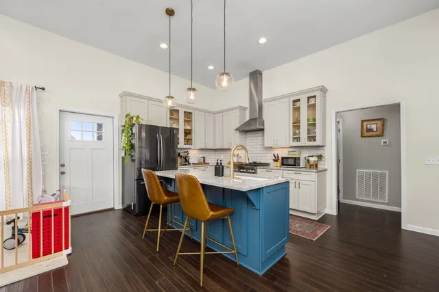 a open kitchen with stainless steel appliances granite countertop a stove a refrigerator a kitchen island a dining table and chairs with wooden floor
