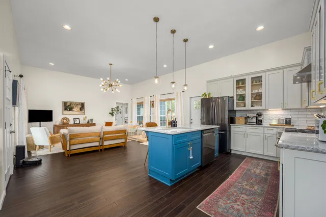 a large white kitchen with kitchen island granite countertop a stove and a wooden floors