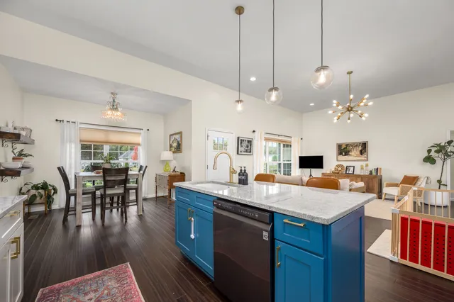 a kitchen with kitchen island granite countertop a stove a sink a dining table and chairs with wooden floor