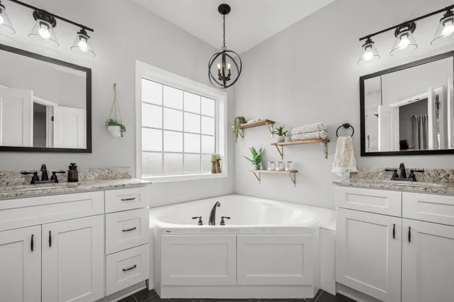 a bathroom with a granite countertop sink vanity mirror bathtub cabinet