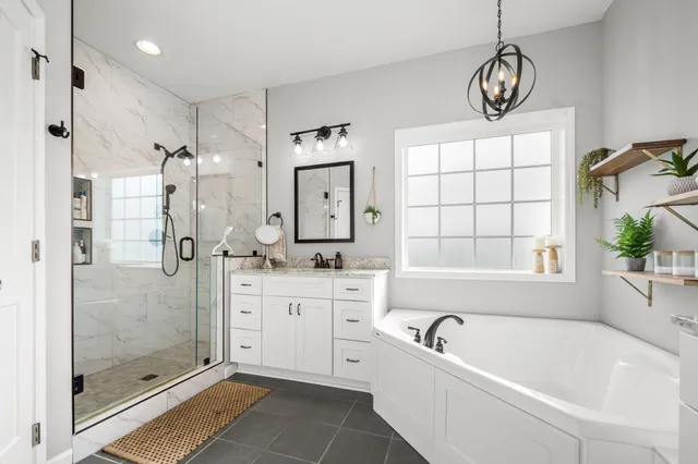 a bathroom with a granite countertop tub a double vanity sink a window and a shower