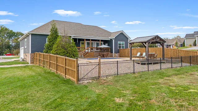 a house that is sitting in the grass with large trees and plants