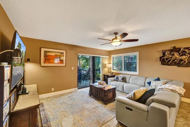 a living room with furniture a flat screen tv and a floor to ceiling window