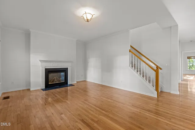 a view of an empty room with wooden floor and a fireplace