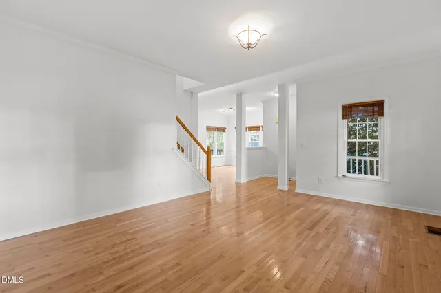 a view of an empty room with a window and wooden floor