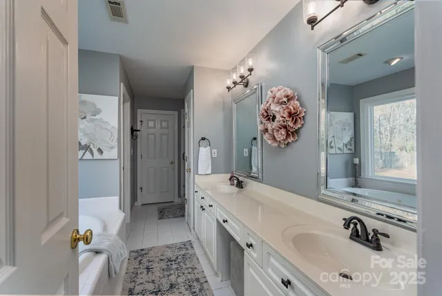 a spacious bathroom with a tub sink and mirror