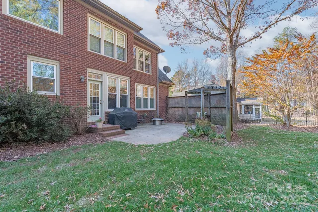 a view of a brick house with a yard and large tree