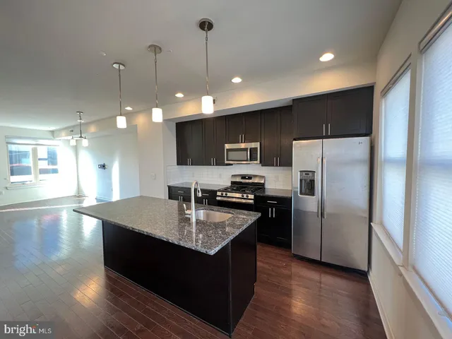 a kitchen with kitchen island stainless steel appliances a sink stove and refrigerator