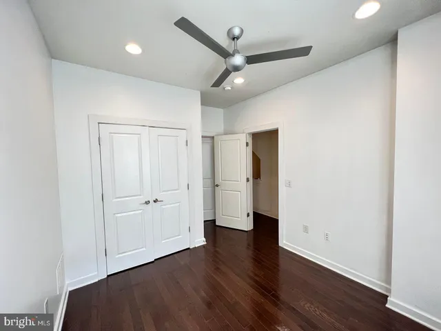 an empty room with wooden floor and a ceiling fan