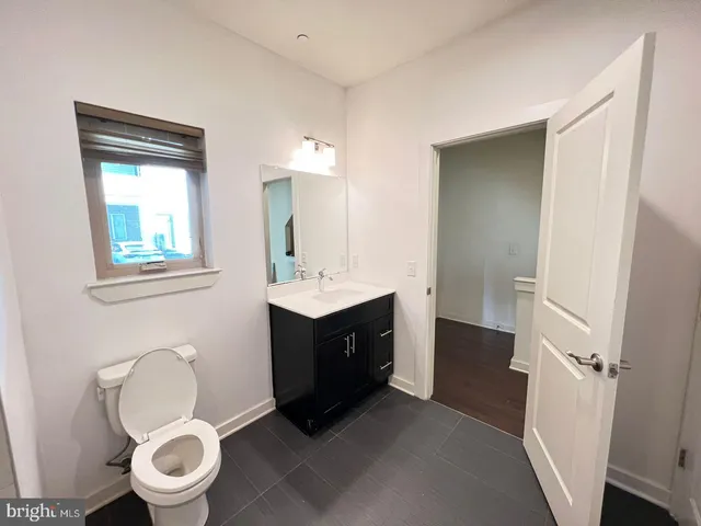 a bathroom with a toilet a sink a mirror and a window