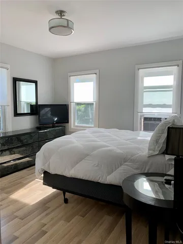 a bedroom with a bed and dresser with wooden floor