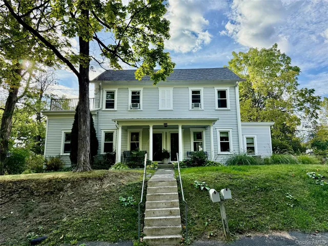 a front view of a house with a yard and potted plants