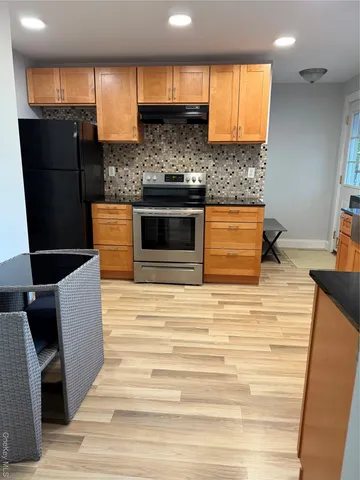 a kitchen with stainless steel appliances kitchen island granite countertop a sink and a refrigerator