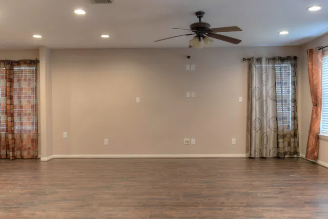 a view of a room with a ceiling fan and hardwood floor