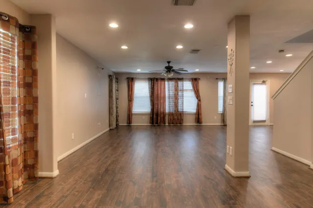 an empty room with wooden floor and windows