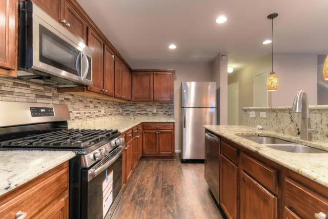 a kitchen with kitchen island granite countertop a sink cabinets and stainless steel appliances