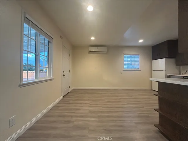 a view of an empty room with window and wooden floor