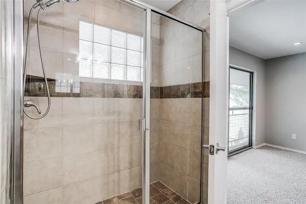 a bathroom with a glass shower door and a window
