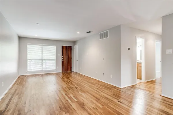 a view of an empty room with wooden floor and window