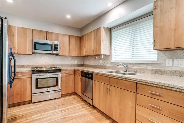 a kitchen with granite countertop a stove a sink and a microwave