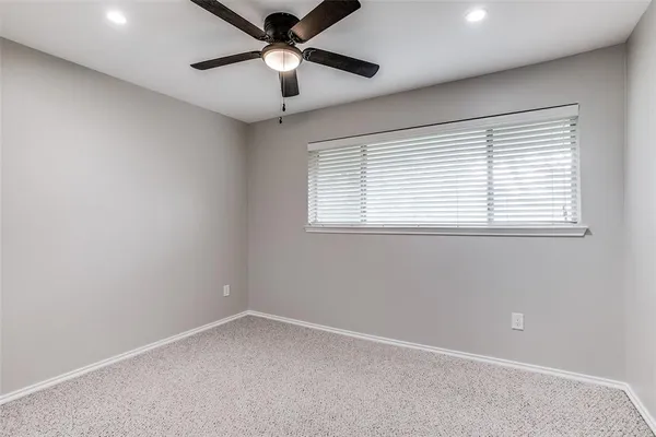 an empty room with a window and a fan