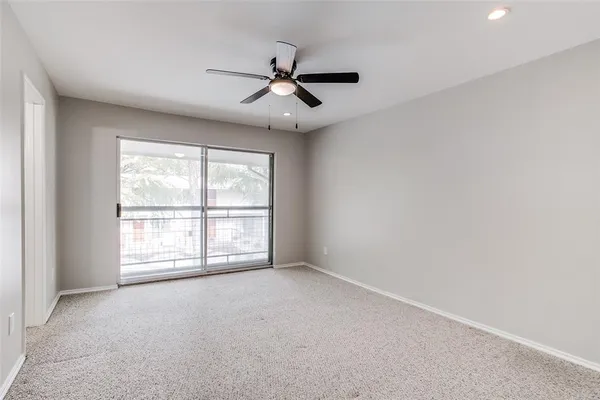 an empty room with windows and ceiling fan