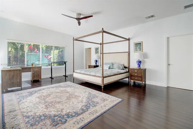 a living room with kitchen island granite countertop wooden floor and a flat screen tv