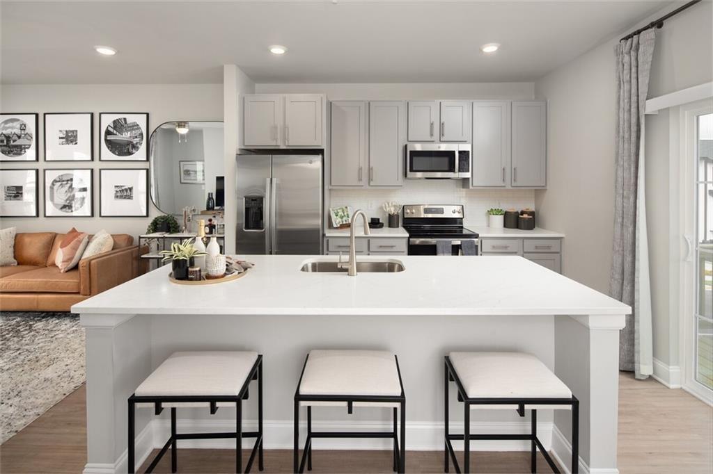 3960 Redan Road, Unit B2 Stone Mountain, GA 30083 - Photo 5 of 23 a kitchen with stainless steel appliances granite countertop a stove a sink a microwave a refrigerator and white cabinets with wooden floor
