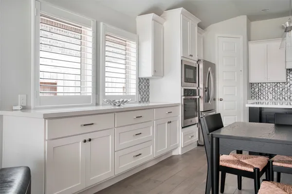 a kitchen with stainless steel appliances a white table chairs and a window