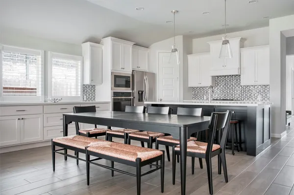 a kitchen with stainless steel appliances granite countertop a table chairs microwave and sink