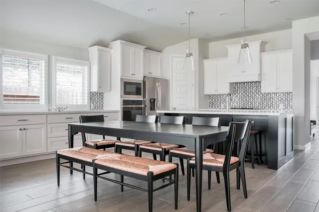 a kitchen with stainless steel appliances granite countertop a table chairs microwave and sink