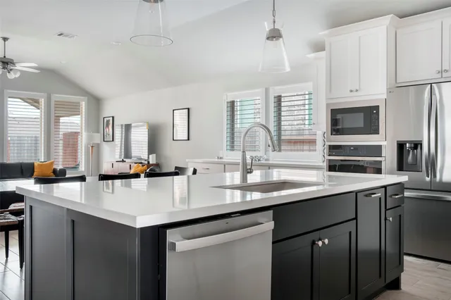 a kitchen with sink a center island and stainless steel appliances