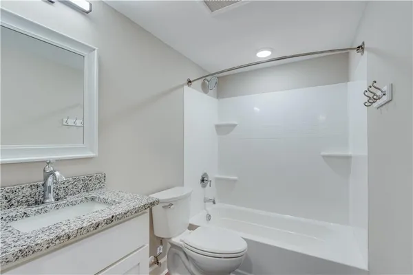 a bathroom with a granite countertop sink toilet and shower