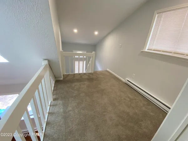 an empty room with a fan & a window