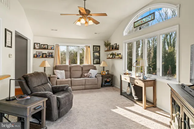a living room with furniture a flat screen tv and a floor to ceiling window