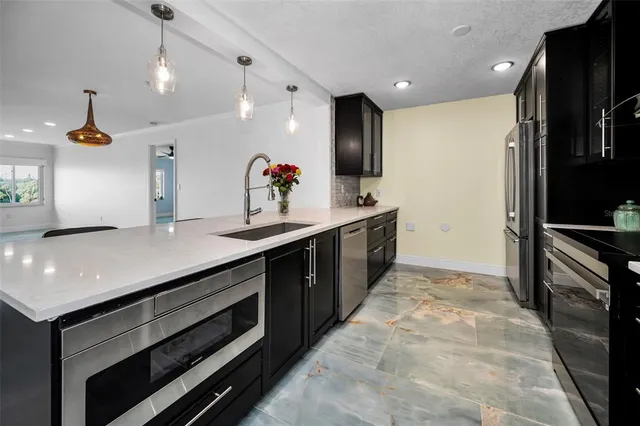 a kitchen with stainless steel appliances kitchen island granite countertop a refrigerator and a sink